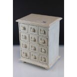 A white tabletop chest of twelve drawers, stands approx 29cm in height.