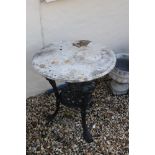 A wrought iron garden table with marble top.