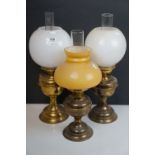 Three vintage brass oil lamps complete with shades and chimneys.