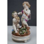 A ceramic figurine of two cherubs with a birds nest, crossed swords mark to base.