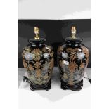 A pair of black ground contemporary lamps with stylized floral decoration.