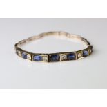 Early 20th century sapphire and paste rose metal bracelet, seven graduated oval blue sapphires,