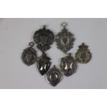 A collection of seven fully hallmarked sterling silver watch fob medallions.