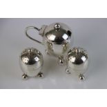 Two silver pepperettes of egg shaped form raised on three ball feet together with a matching