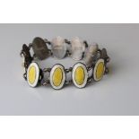 Early 20th century enamelled silver panel bracelet, eleven oval yellow and white enamelled panels,