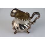 Silver cream jug raised on four scroll feet, bulbous body, acanthus leaf scroll handle, stamped