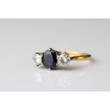 Sapphire and diamond three stone 18ct yellow gold platinum set ring, the oval mixed cut blue-black