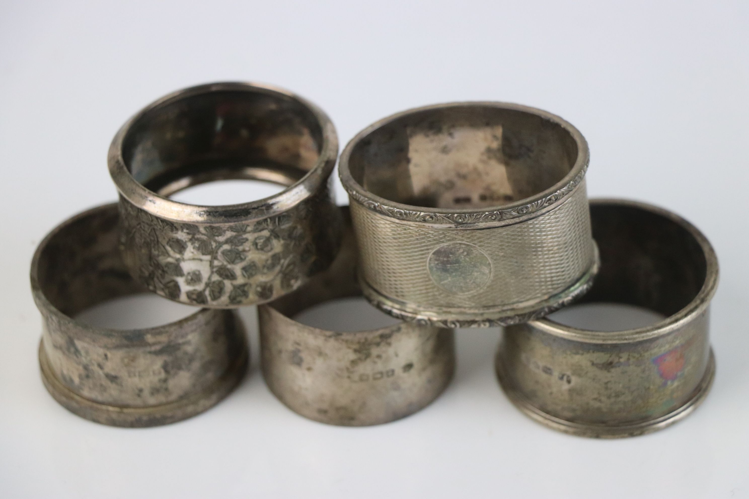 A group of five fully hallmarked sterling silver napkin rings, various makers and assay marks.