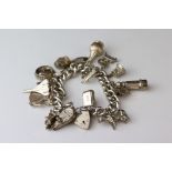 Silver curb link charm bracelet with padlock clasp and sixteen silver and white metal charms