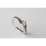 Diamond 18ct white gold crossover ring, the principle round brilliant cut diamond weighing approx