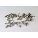 Silver curb link bracelet with padlock clasp and fourteen silver and white metal charms