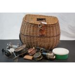 A vintage wicker fishing basket together with a quantity of fishing reels.