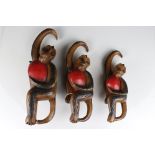 Three Carved Wooden Hanging Monkeys holding Fruit, largest 36cms high