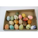 A collection of nineteen caved stone and ceramic ornamental eggs.