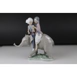 A Lladro figure of a young couple riding an elephant.24 cm tall.