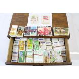 A collection of loose cigarette and tea cards contained within a wooden box.