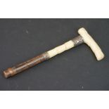 An antique ivory parasol handle with white metal mounts.