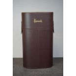A brown leatherette wine bottle holder embossed Harrods to the top.