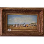 A gilt framed oil painting of a beach scene with figures, with indistinct signature 18 x 40 cm.