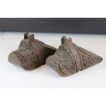 A pair of antique wood and metal mounted stirrups with carved leaf decoration.