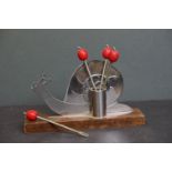 A Snail cocktail stick holder on wooden base with four cocktail forks.