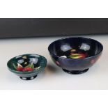 A blue ground Moorcroft bowl with leaf and berry decoration af and a similar green ground bowl