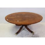 Reproduction Mahogany Effect Oval Coffee Table raised on four splay legs with brass castors,