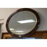 An antique oval mahogany inlaid bevelled edged mirror with shell decoration.