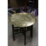 An Asian brass topped folding table with camel decoration.