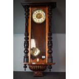 A wooden and glass cased wall clock with brass pendulum.