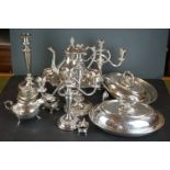 A box of silver plated items to include candle sticks, water jug and cruet set.