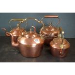 A collection of four copper kettles of varying sizes with brass fittings.