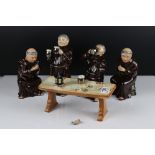 A group of four ceramic Monk figures together with table.