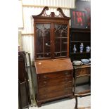 George III style Mahogany Bureau Bookcase by Baker with broken swan neck pediment, above twin astr