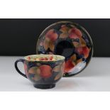 A Moorcroft Pottery cup and saucer with Pomegranate decoration, blue impressed mark and signature