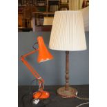 A orange angle poise lamp together with a wooden table lamp.