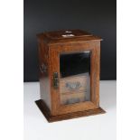 An oak early 20th century smokers cabinet with with glazed door and two drawers.