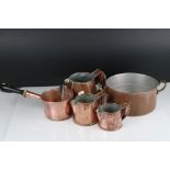 A set of three graduated copper jugs together with two copper pans.