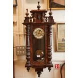 A vintage ornate wooden cased chiming wall clock with pendulum movement, complete with key.
