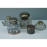 A collection of five inkwells two include two hallmarked silver topped examples and a travelling