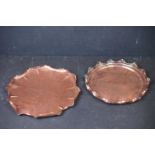 Two arts and crafts circular copper trays with crimped edges, one with central floral decoration.