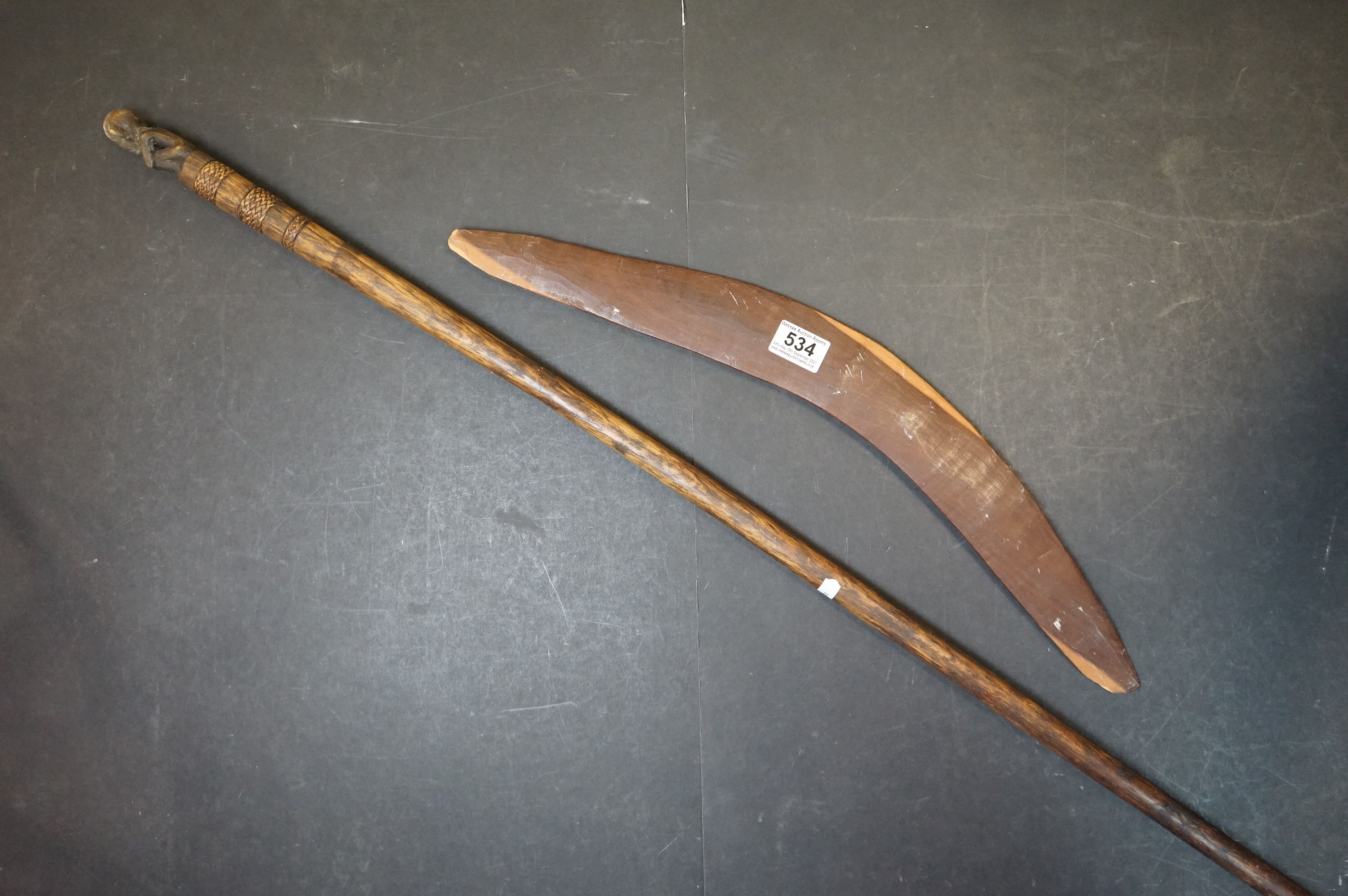 A vintage carved wooden boomerang with Emu decoration and a Wooden Staff