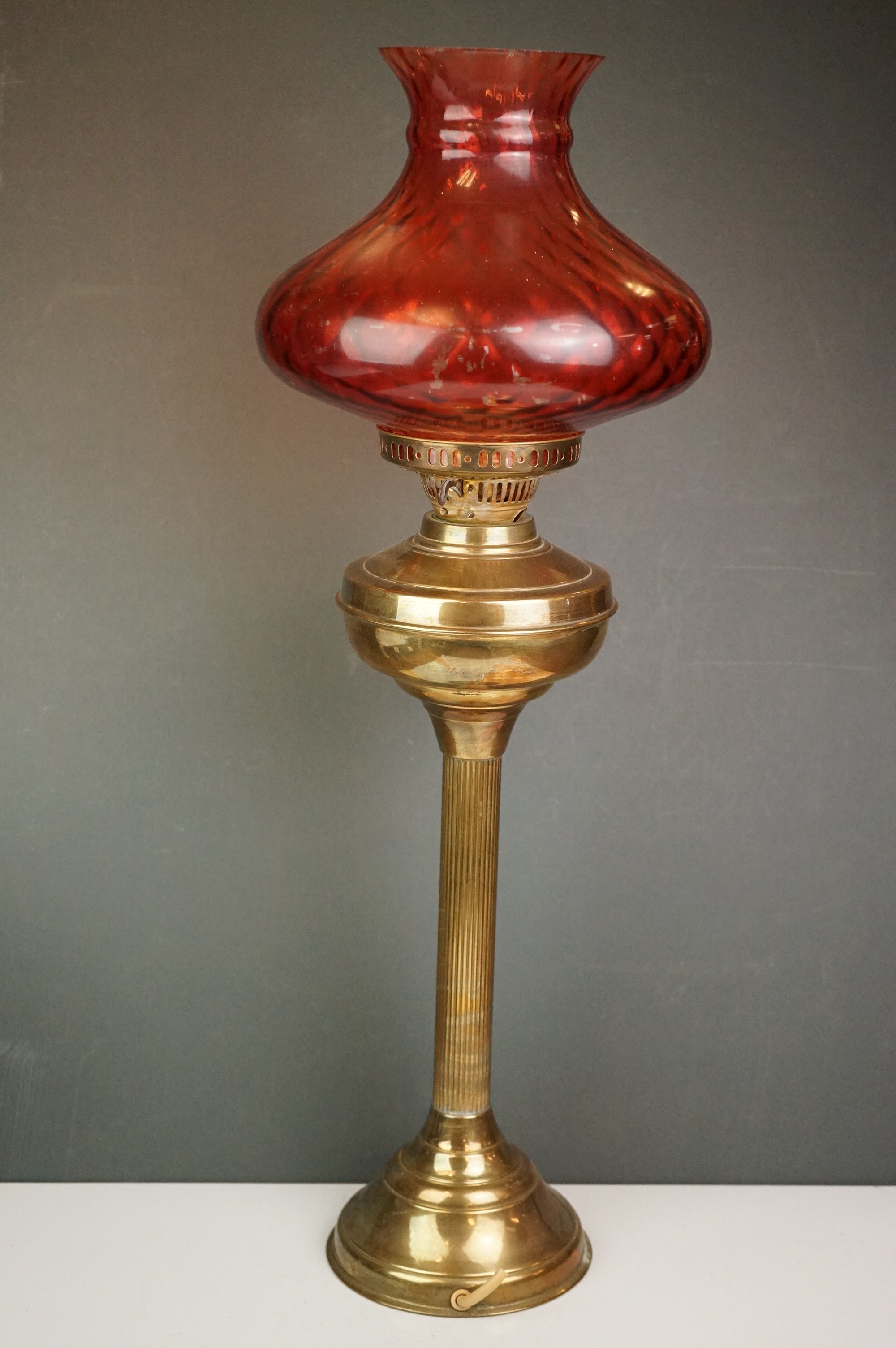 A vintage brass oil lamp with orange glass shade converted to electric.