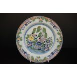 An antique Bristol Delft plate with blue, red, green and yellow floral decoration.