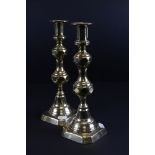 A pair of antique brass candle sticks with pusher rods.