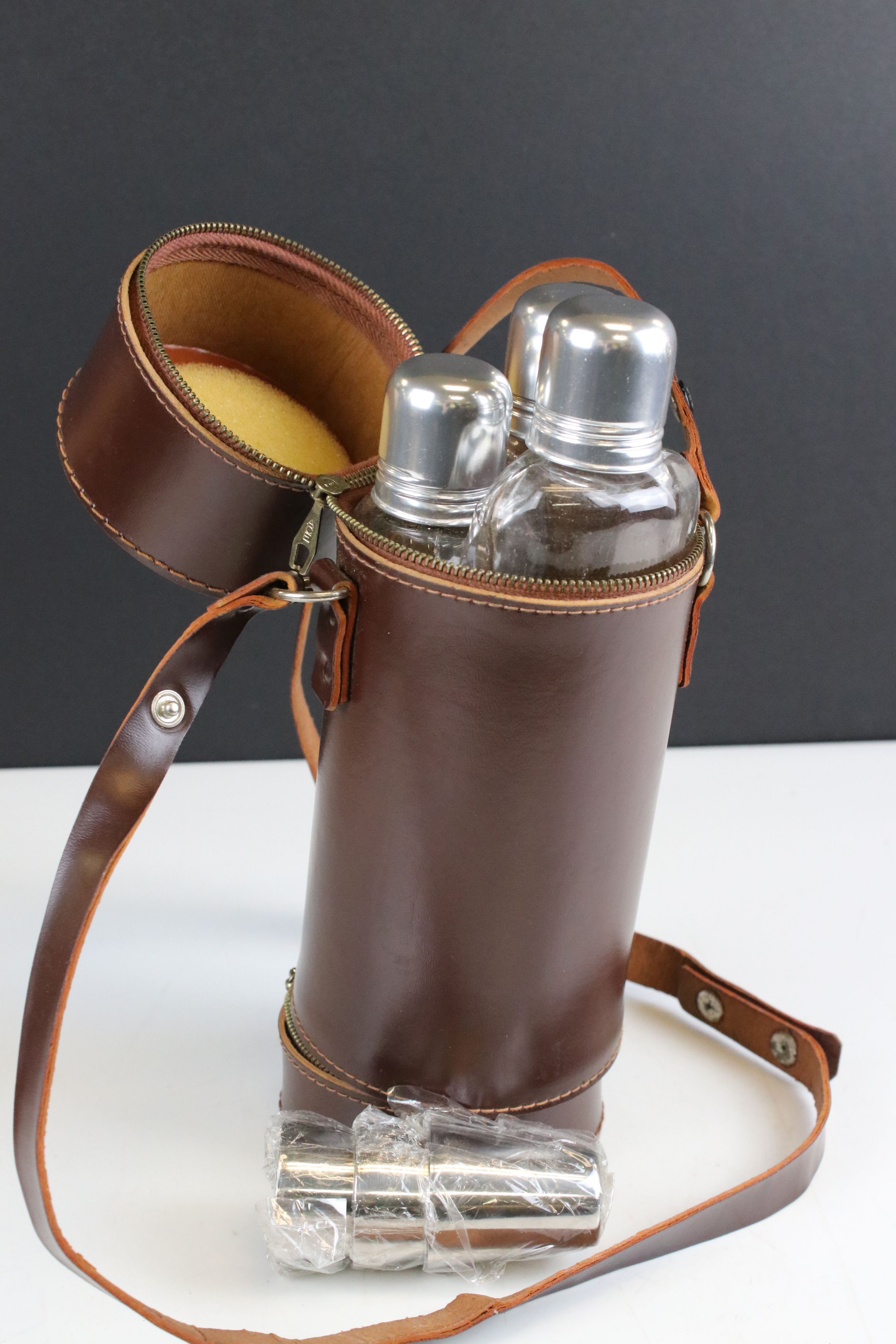 Leather cased triple spirit flask, set with three cups in separate compartments