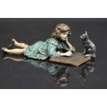 Cold painted bronze figure of a child writing on a board, with her cat