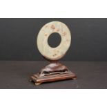 An oriental carved jade ring on wooden stand.