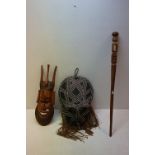 A collection of three items of tribal art to include two masks and a wooden staff.