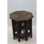 Indian hardwood Octagonal Table, heavily carved with flowers and foliage to top and raised a folding